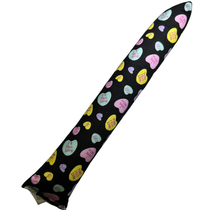 A black Valentine’s catnip kicker toy with colorful conversation hearts and playful designs, great for kicking and pouncing Made by CatnipTakeout.