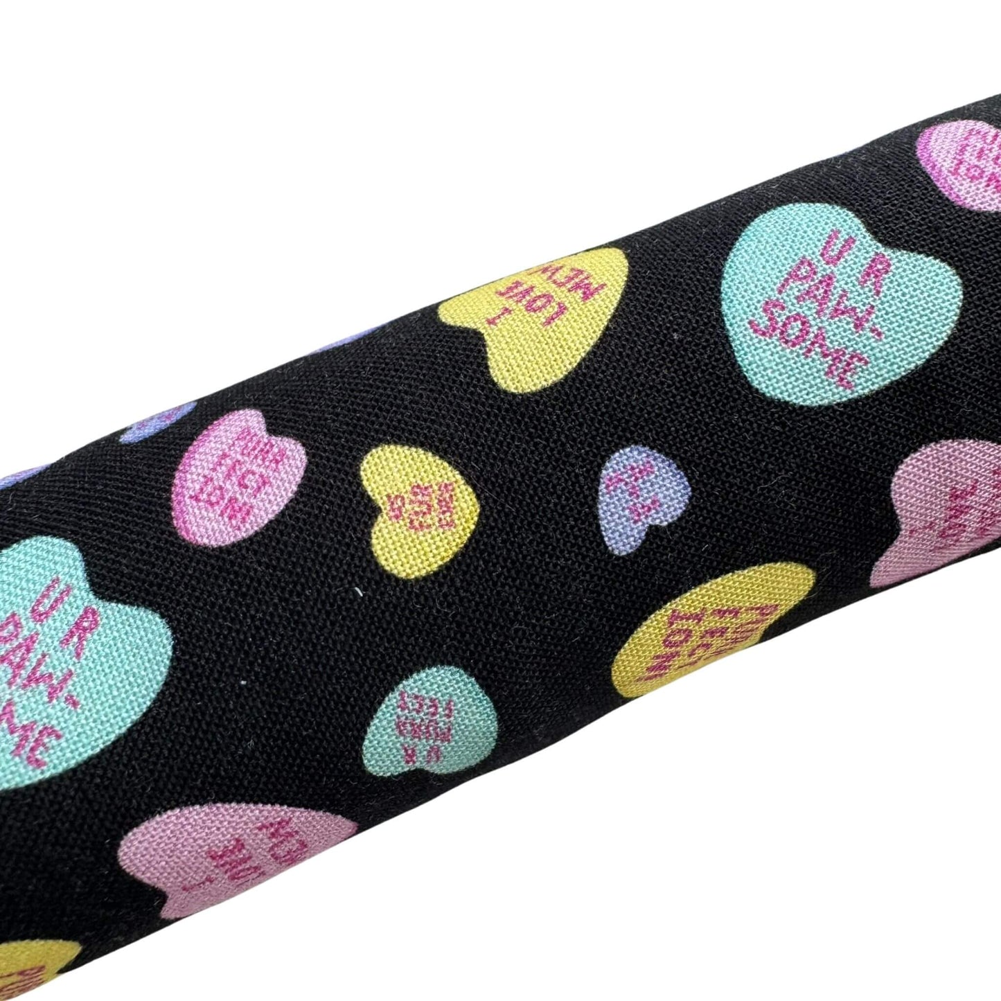 A black Valentine’s catnip kicker toy and with colorful conversation hearts and playful designs, great for kicking and pouncing Made by CatnipTakeout.